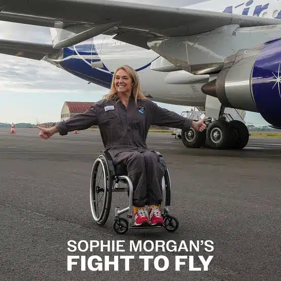 Sophie Morgan sits in her wheelchair arms spread wide smiling in front of a plane with the words Sophie Morgan's Fight to Fly in white text.